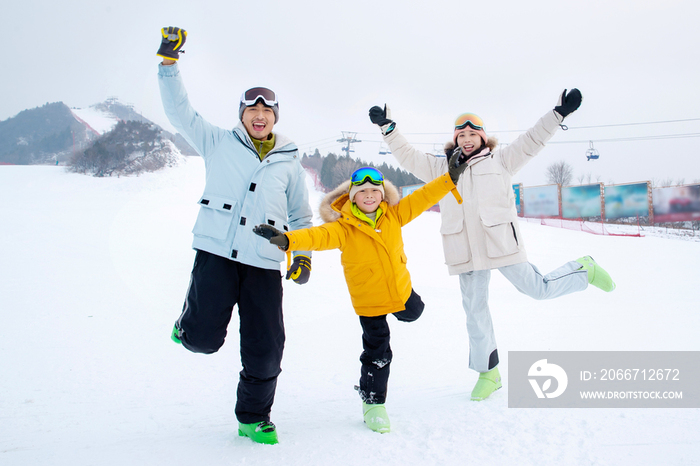 快乐的三口家庭在雪地上嬉戏