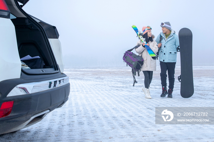 停车场上青年伴侣拿着滑雪板