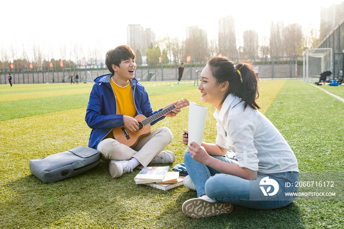 青年大学生在校园里弹奏吉他