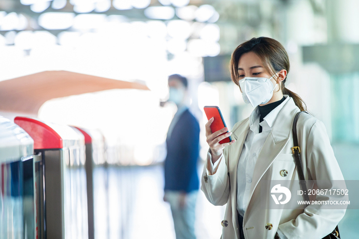 戴口罩的年轻女人站在地铁站台上