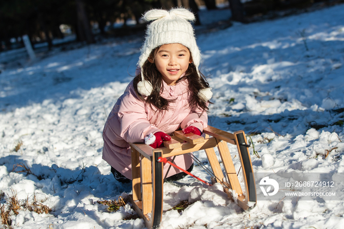 快乐的小女孩在雪地上玩雪橇