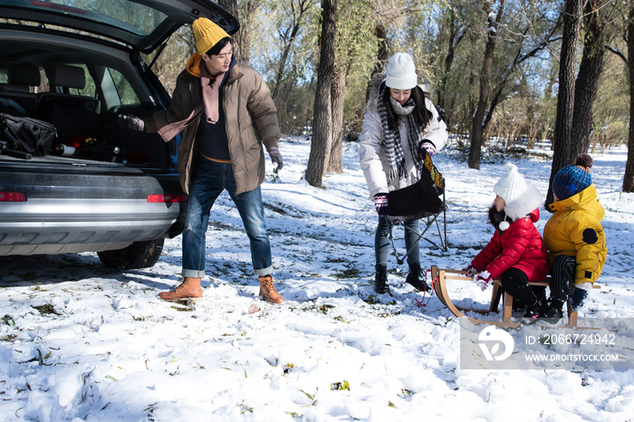 在雪地上准备玩雪橇的一家人