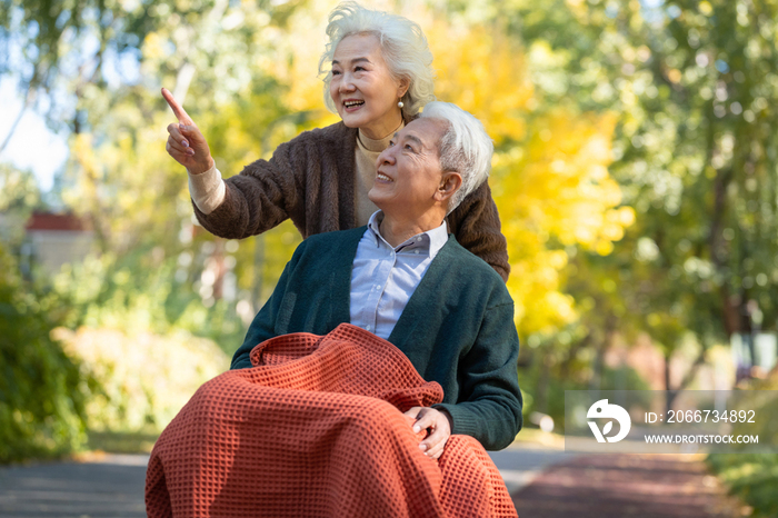 老年女人推着坐轮椅的老伴散步