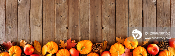 Fall border with pumpkins, leaves and apples. Top view on a rustic dark wood background with copy sp