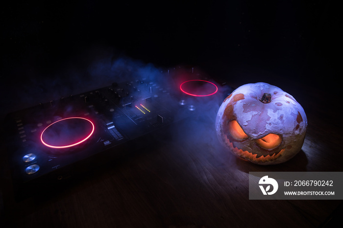 Halloween pumpkin on a dj table with headphones on dark background with copy space. Happy Halloween 