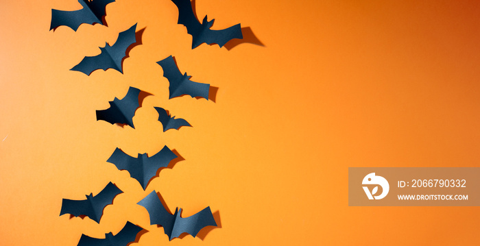 Halloween photo of black bats flying up on blank orange background.