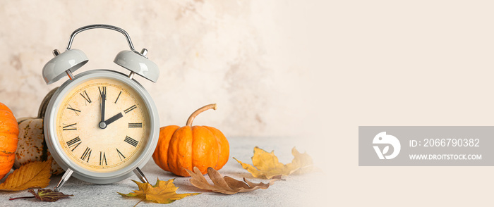 Alarm clock and autumn leaves with pumpkins on light background. Banner for design