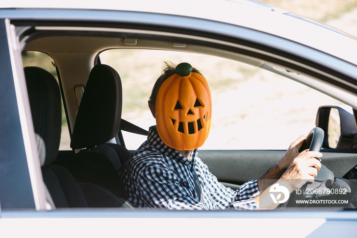 Man inside a car with a pumpkin mask of jack o lantern Hallowwen