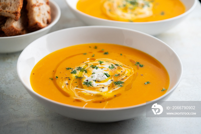 Pumpkin soup served in a bowl with croutons, parsley and olive oil.