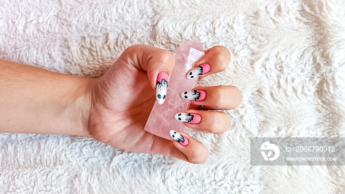 Girl with halloween themed nails on fluffy white blanket holding rose quartz. Aesthetic Isolated on 