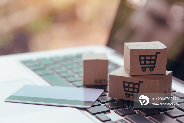  Shopping online. Credit card and cardboard box with a shopping cart logo on laptop keyboard. Shoppi