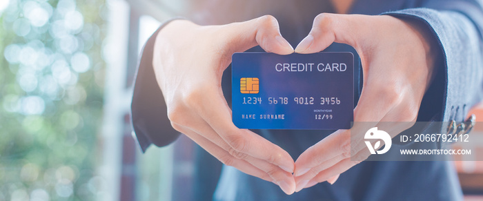 Female businessmen are holding a credit card and making a heart-shaped hand.