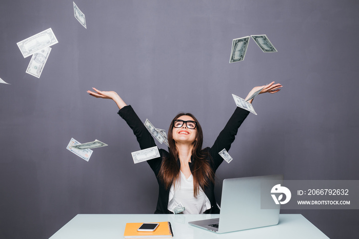 Business woman at her office working place throw the Money flying over laptop