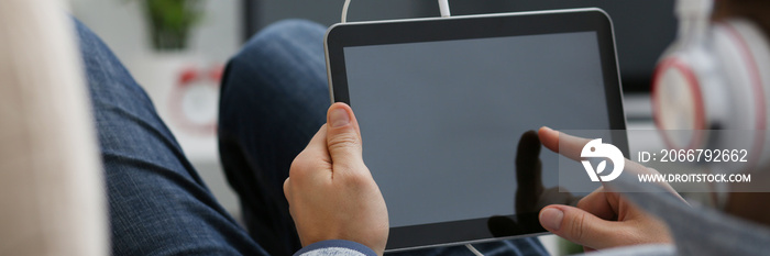 Male hand holds tablet in home setting while