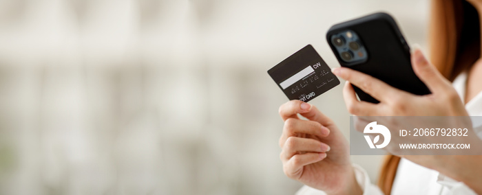 Close up hand of business Woman using a credit card and mobile smartphone for payments and online sh