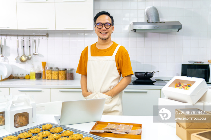 Portrait of Asian man bakery shop owner using laptop computer advertising online bakery store on soc