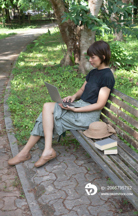 Woman sitting on old bench,in a park,using laptop