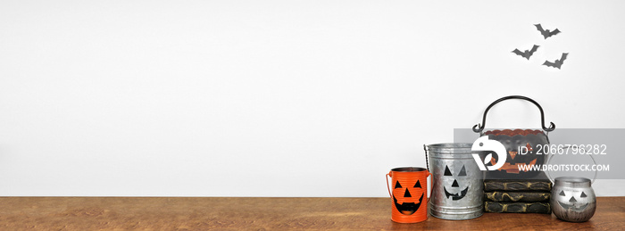 Halloween decor on a wood shelf. Rustic metal jack o lantern candle holders against a white wall wit