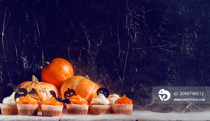 cupcakes and pumpkins to celebrate halloween on a background with space for text