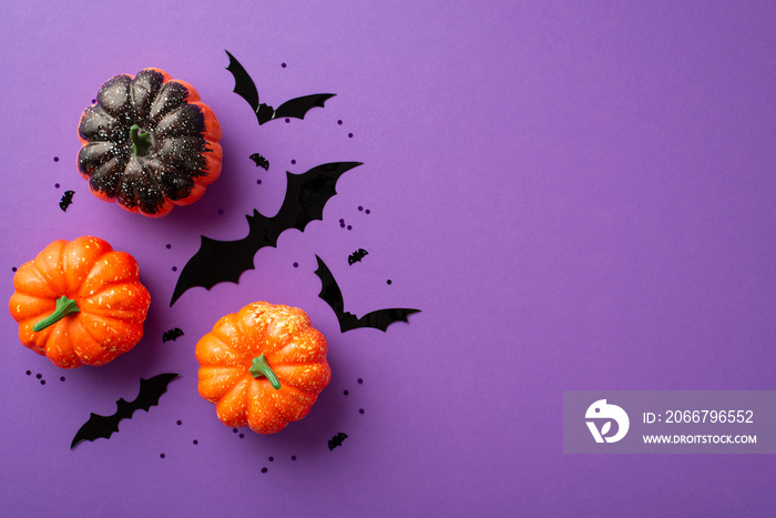 Halloween concept. Top view photo of pumpkins bat silhouettes and black confetti on isolated violet 