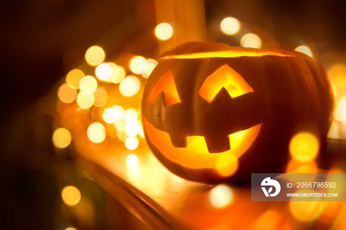 A cheerful smiling Jack O Lantern on halloween placed on a fireplace with fairy lights