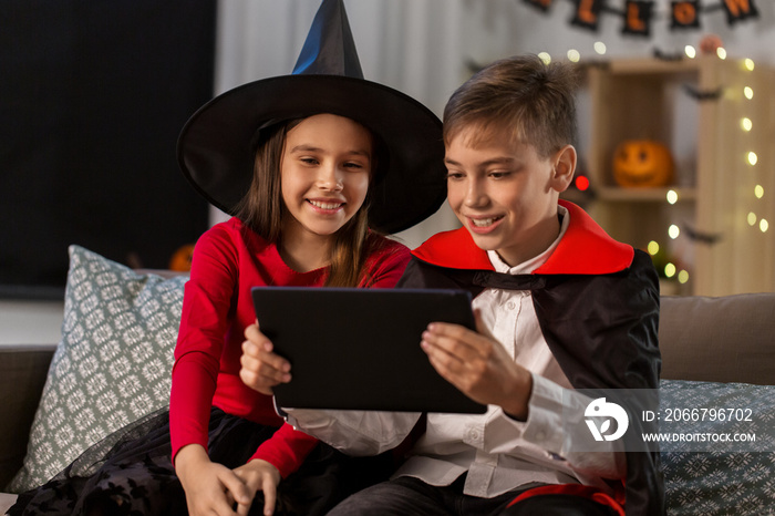 halloween, holiday and childhood concept - smiling boy and girl in party costumes of witch and dracu