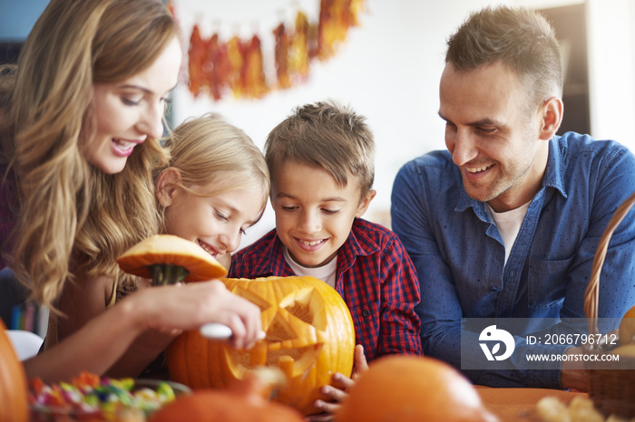 Parents helping children in carving pumpkins