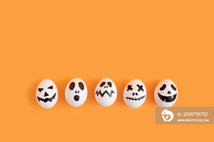 Simple Halloween concept with white eggs painted as ghost characters.