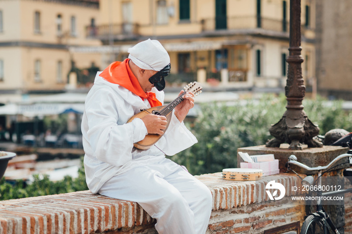 The mask of Pulcinella (Punchinello) plays the mandolin on the Naples promenade