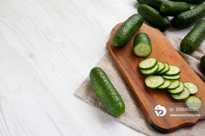 Fresh mini baby cucumbers on a rustic wooden board, low angle view. Space for text.