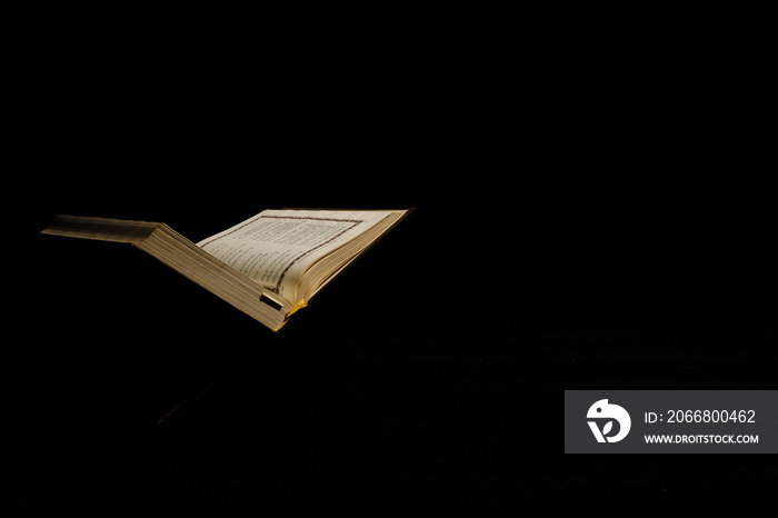 Selective focus and low light picture of Holy Quran at copyspace dark background.