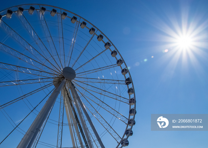 Bright sun shines over recreational ferris wheel