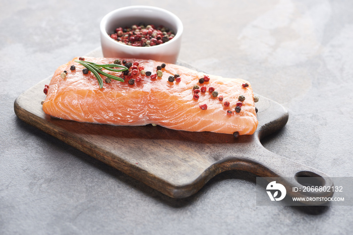 raw fresh salmon with peppercorns and rosemary on wooden cutting board