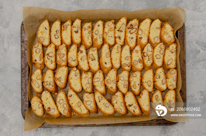 Traditional Italian cantuccini cookies with almonds on a baking sheet on a gray concrete background. Recipe step by step.