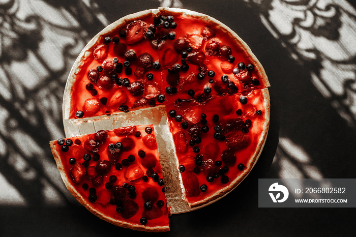 Slice of red jelly cake with strawberries and blueberries.