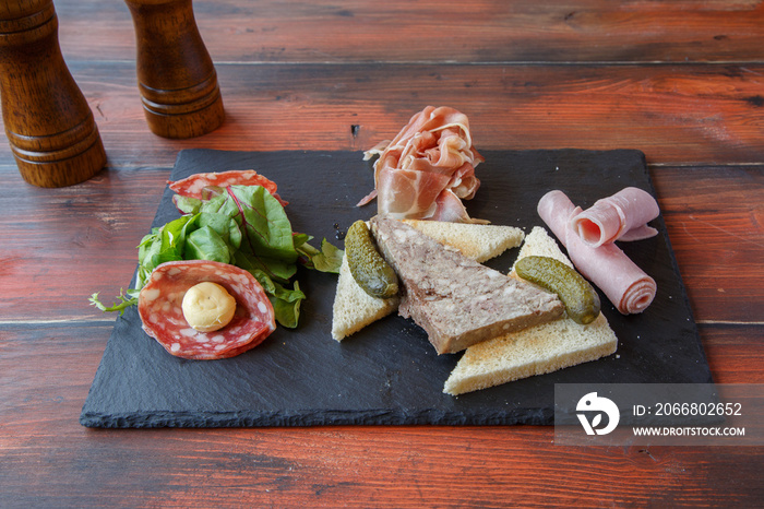 Planche de charcuterie sur une ardoise (paté de campagne, saucisse, jambon, cornichon)