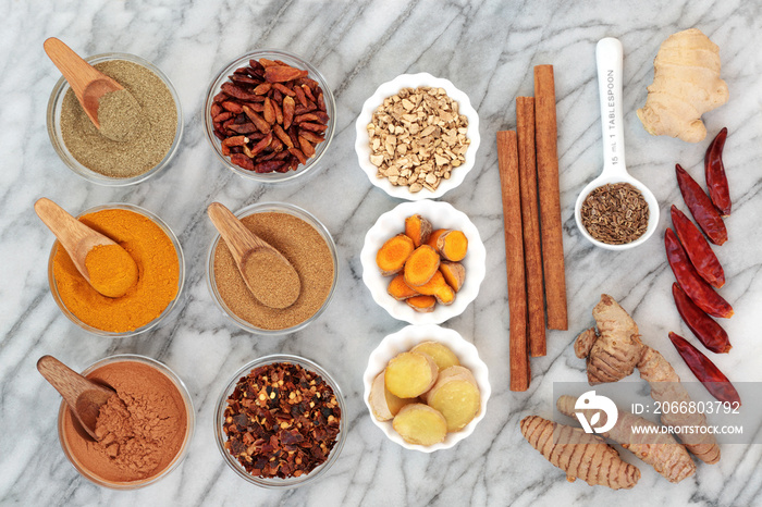 Fat busting spices for weight loss with fresh and dried turmeric,  ginger, cumin, chilli, cinnamon and gymnema sylvestre used to suppress appetite. Top view on marble background.