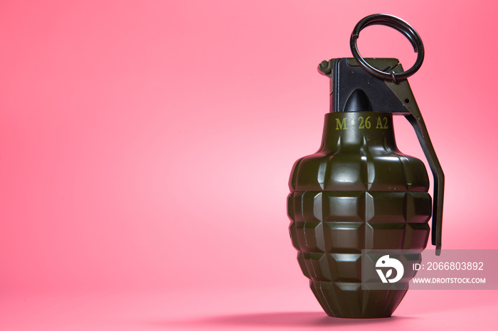 Green metal hand Grenade with round pin over When I pull out it will blow Bomb On a pink background