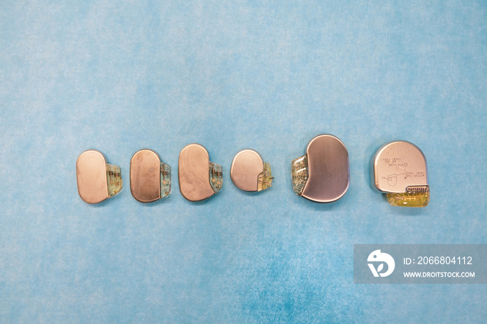 some various pacemakers and implantable defibrilators lie on a light blue base