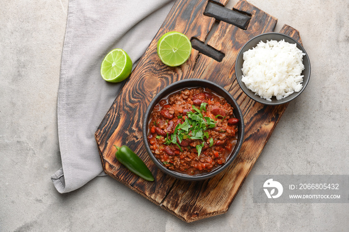 Bowls with tasty chili con carne and rice on grey background
