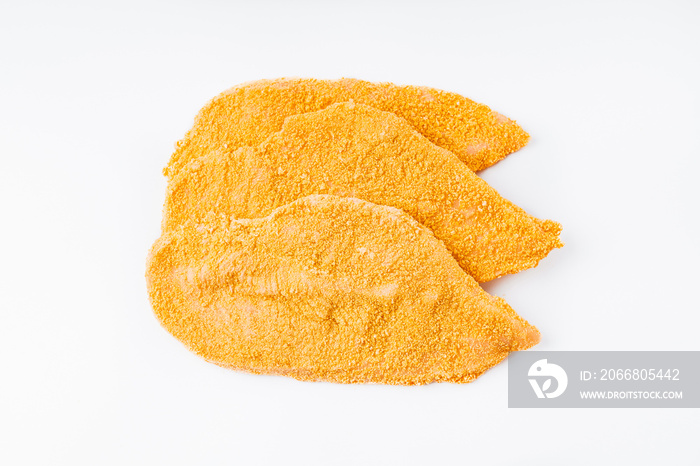 Three slices of breaded schnitzel, sliced on a white background. Raw chicken fillet sprinkled in a bright breading.