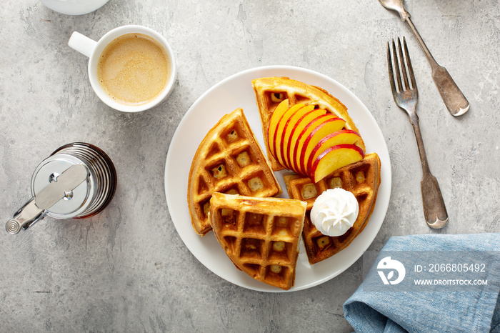 Peach waffles for breakfast served with fresh berries, maple syrup and coffee