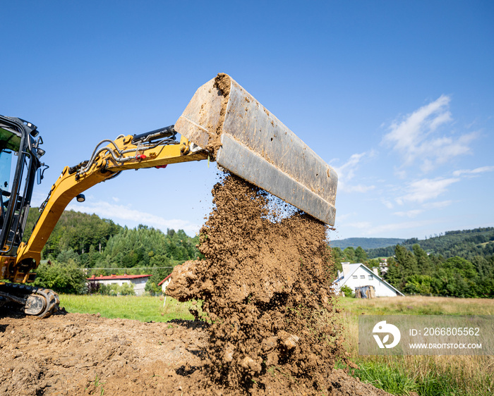 Mini excavator digging preparing ground under home garden