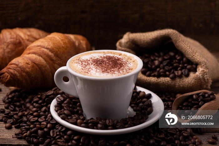 Cappuccino and croissant with coffee beans