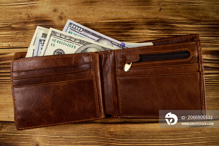 Opened wallet with american dollars on wooden table. Top view