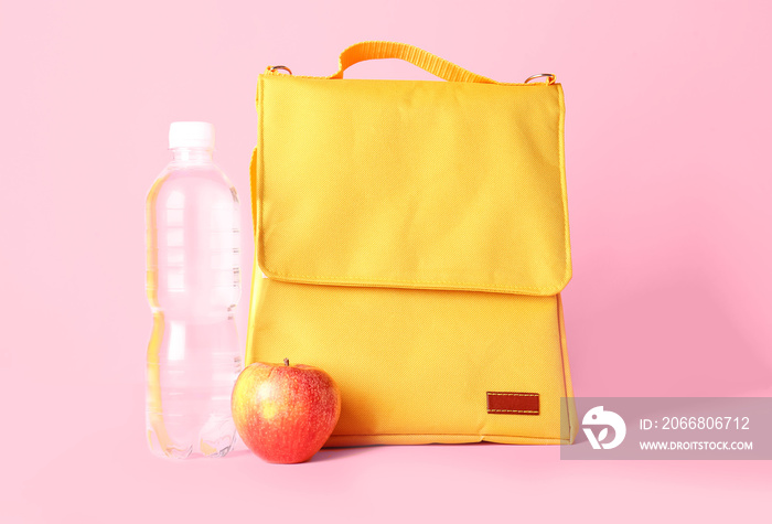 Lunch box bag, bottle of water and apple on color background