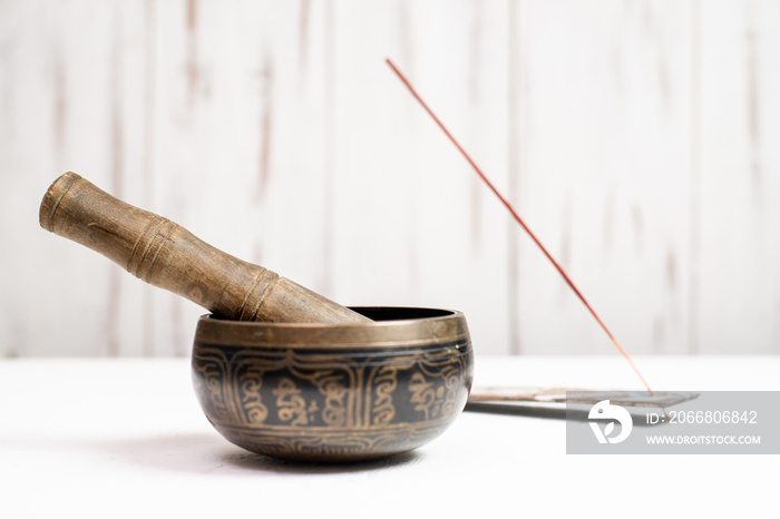 Singing bowl and incense stick on a light wooden background. Yoga, meditation concept.