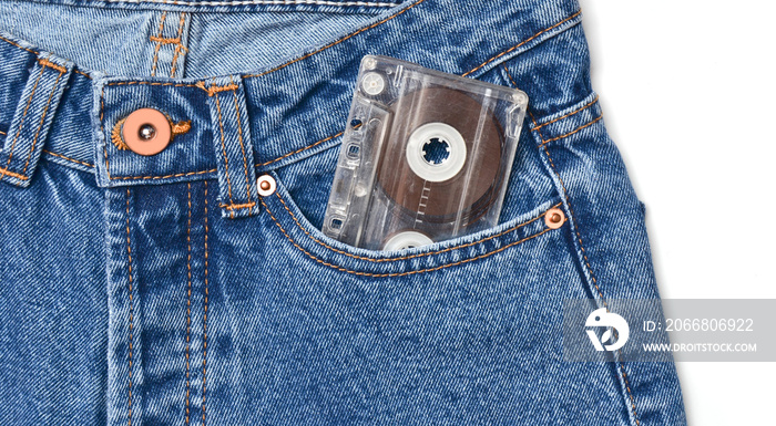 Audio cassette in a pocket of old-fashioned blue jeans and isolated on a white background.