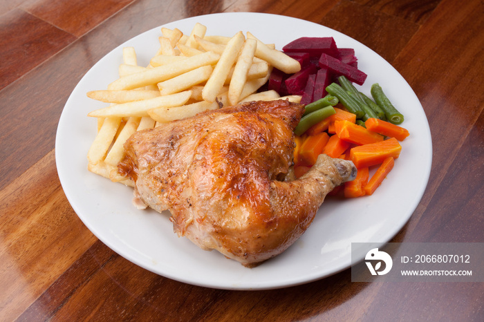 Peruvian food: pollo a la brasa or roasted chicken with french fries and cooked vegetable salad served on a white plate