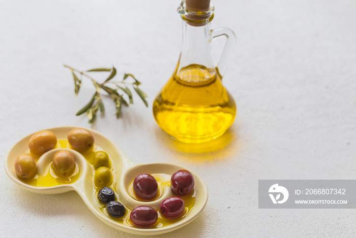 Olive oil and olives image on white insulated table. Generally, olive oil is used in salads, stuffed peppers and cooking.